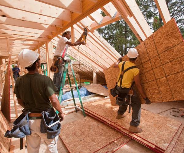 A group of men working on the roof of a house.