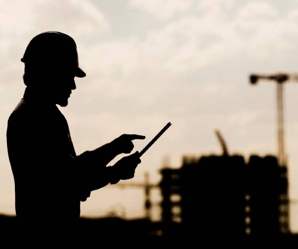 A man in hard hat holding a tablet.